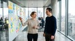 © Cahya - Dynamic professional man and woman discussing project ideas on a glass whiteboard with sticky notes, portraying collaborative office brainstorming