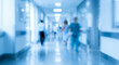 © birulaut - A blurred view of a hospital corridor, featuring people walking and bright lighting, conveying a sense of motion and activity in a healthcare environment.