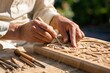 © Studio - Artisan hands of experienced craftsman carving intricate floral patterns on wooden block with chisel in outdoor workshop, focused traditional woodwork concept, close-up shot with soft natural light.