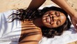 © Anna - Smiling woman lying on a beach towel with palm leaf shadows on her face. Summer skincare and sun protection concept. Happy young black woman enjoying a tropical vacation