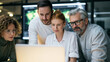 © CreativeArt - Diverse business team collaborating closely, analyzing data on a laptop screen during a professional meeting in an office environment