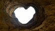 © Travel 'n' Lifestyle - View of a heart-shaped opening in the ceiling of a limestone sea cave looking up towards the bright sky in Albufeira, Faro District, Portugal.