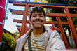 © Edu Bastidas + David Garcia/Stocksy - Smiling traveler taking selfie near red torii gates in Tokyo