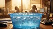 © Olga Ко - Blaue Plastikschüssel mit Eiswürfeln und Wasser auf einem Schreibtisch im heißen Büro, verschwommene Mitarbeiter im Hintergrund. Konzept für Sommerhitze, kaputte Klimaanlage oder Abkühlung am Arbeits