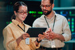 © Zamrznuti tonovi - It professionals cooperating in data center, discussing software development and network administration with tablet