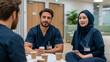 © pattozher - Healthcare Professionals in Discussion: A male and female healthcare professional, one wearing a hijab, engage in a focused discussion over coffee.