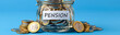 © pattozher - Pension Fund in a Jar: A glass jar filled with coins, labeled PENSION, sits on a blue background, flanked by stacks of coins, symbolizing savings and financial planning for retirement.