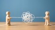 © Belawa art - Two wooden figures pulling a tangled string concept of resolving conflict untangling a problem and teamwork communication