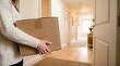 © soojin - Close-up of a woman's hand carrying a box as she enters the house