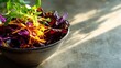 © Rinna - A fresh salad with shredded red cabbage sliced carrots and green herbs served in a dark ceramic bowl on a gray surface