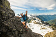 © Cavan Images - Happy hiker scrambles up a rocky mountain peak