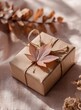 © C - A simple gift box wrapped in kraft paper, tied with twine, and adorned with a delicate pink autumn leaf. Soft, muted colors
