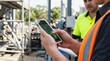 © TheseusStock - Construction Worker Using Mobile Phone Application for Site Management and Digital Planning at Industrial Project Site