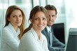 © Gupta - Three diverse business professionals in white shirts smiling and working together in an office.