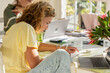 © Marc Romanelli - young woman working with laptop in casual small business environment