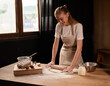 © Volodymyr_sh - Happy woman baking fresh homemade pastry in kitchen, rolling dough with flour, milk, and eggs