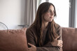 © luciano - Woman feeling lonely and sad, looking away, reflecting on worries and mental health while sitting on a couch at home