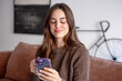 © luciano - Young woman relaxing on sofa, eyes closed in bliss, smiling while holding smartphone at home