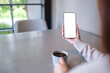 © Farknot Architect - Mockup image of a woman holding mobile phone with blank desktop screen and drinking coffee