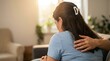 © ShazilStock - Woman sitting and receiving comfort while being held by partner, cozy home living room background with soft backlight from a nearby window during daytime
