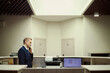 © DragonImages - Wide shot of Caucasian middle aged hotel receptionist speaking on desk phone at front desk, managing guest service communication. Ideal for hospitality, travel booking, customer support