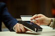 © DragonImages - Close up of female customer holding bank card over payment terminal during hotel checkout, making contactless transaction. Ideal for travel booking, hospitality service, cashless payment marketing