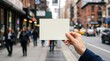 © Sumaiya - Hand holding blank white card on city street with blurred background