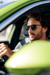 © Natali - young curly positive man driving a car