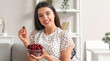 © Pixel-Shot - Happy beautiful young woman with bowl of ripe cherries sitting on sofa in living room