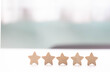 © mangolovemom - Five star rating review customer feedback satisfaction quality service reputation evaluation wooden star row white table, minimal background, bright light, positive satisfaction concept with copy