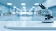 © Benjawan - Futuristic clean medical laboratory background with a microscope on a sharp focused white table and blurred research facility with large copy space.