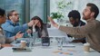 © Yuliia - Overworked exhausted business team leader boss woman suffer headache group of managers arguing with paperwork at office briefing. Businesswoman stressed with migraine multiethnic workers argue shout