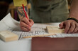 © Seventyfour - Close up of young adult craftsperson marking carpentry plan beside wood samples in workshop, planning custom woodworking project. Ideal for artisan business, trade training marketing