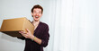 © Julia - A package delivery moment with a young man holding a box indoors.