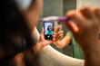 © Marko Geber - Woman brushing teeth taking mirror selfie in bathroom