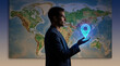 © MD SHAHIN - A businessman holds a glowing blue digital location pin over a detailed physical world map, representing global navigation, logistics, and international business.