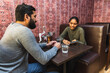 © Diego Martin/Stocksy - Indian couple dining and using phone at table
