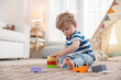 © New Africa - Little boy playing with colorful blocks on floor at home, space for text