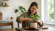 © Vitaliy - Smiling caucasian woman in 30s repotting houseplant with soil on wooden table indoors, home gardening and slow living concept