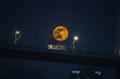 © Travel 'n' Lifestyle - View of a large orange full moon rising behind the cables and deck of the Nanpu Bridge with a bus driving across at night in Shanghai, China.