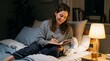 © PSCREATIVE - Woman writing in journal on bed at night with warm lamp light and cup of tea