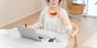 © buritora - A stylish woman relaxing at the dining table in the living room during teatime.