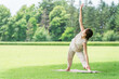 © buritora - A young Asian woman doing park yoga, yoga, Pilates, and stretching in a forest/park (triangle pose).