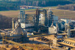 © Amazing Aerial - Aerial view of a wood processing factory with industrial machinery, silos, and piles of wood chips in a rural landscape in Poland.