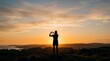 © Ozi - Silhouette of a person making a heart shape with their hands against a vibrant sunset over a scenic landscape with distant water.
