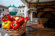 © massimo_g - Cestino di peperoni rossi e gialli su banco gastronomico con spillatrice di bevande e forno sullo sfondo. Scena vivace ideale per temi cibo, mercato, street food e ristorazione.