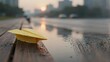 © Sergej - Yellow paper airplane resting on wet park bench at sunset