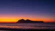 © sri - Serene sunset over calm waters with a majestic mountainous island silhouette