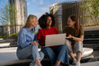 © Nenad - University students working on AI startup idea outdoors with laptop