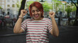 © Krakenimages.com - Woman with hands clasped in prayer on a cobblestone street, striped shirt and red hair, eyes closed and smiling, wrists showing watch and bracelet; gratitude.